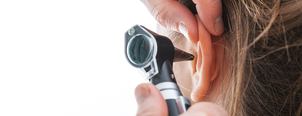 Close-up image of a hearing professional tool being inserted into a patient ear